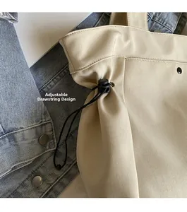 Detail of cream canvas tote bag featuring an adjustable black elastic drawstring buckle