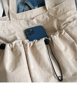 Detail of beige canvas tote with drawstring pocket holding a smartphone for storage