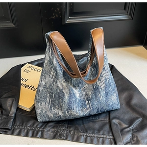 Detail view of large denim tote bag with silver sequins and brown leather handles