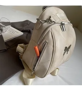 Detailed close-up of quilted cream backpack with metal butterfly and side pockets