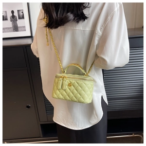 Detail of light green quilted mini box bag with gold flower clasp and chain strap