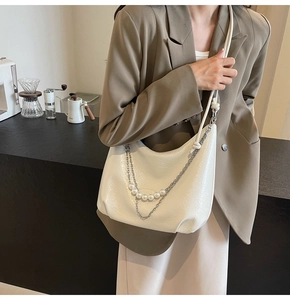 Dettaglio della borsa in pelle pieghettata bianca con perle e catena in metallo