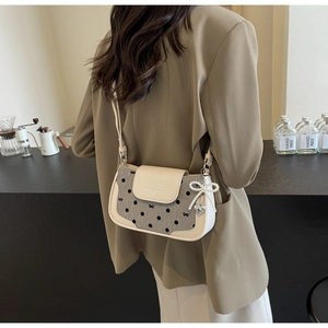 Detail showing beige leather stitching with gray polka dot fabric and a heart pendant