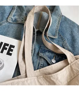 Detail of smooth shoulder straps on a beige pleated nylon tote bag with fine stitching
