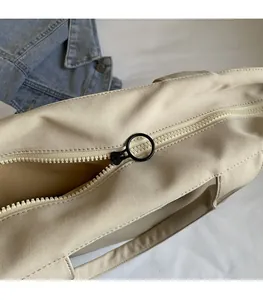 Close-up of smooth beige canvas tote zipper featuring a stylish black circular pull ring