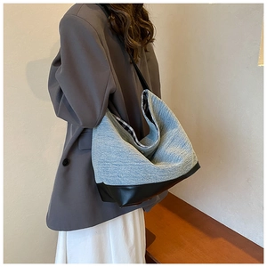 Detail of denim and leather patchwork tote with black straps and plaid lining for women