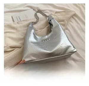 Detail of silver metallic hobo bag featuring pleated texture and heart-shaped metal buckle