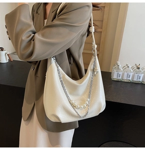 Dettaglio della borsa hobo crema con catena argentata e ciondoli con perle bianche chic