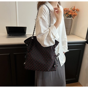 Detail view of black tote bag with red heart pattern and silver chain shoulder strap