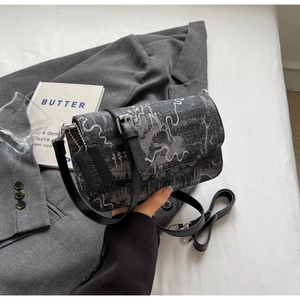 Detail of artistic landscape pattern bag with black leather strap in lifestyle setting
