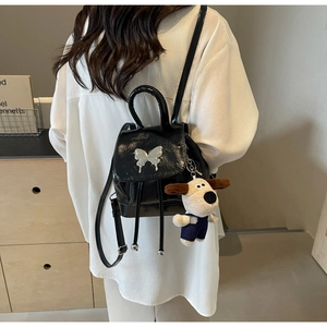 Vue détaillée du mini sac à dos noir brillant avec fermoir papillon et charme en peluche