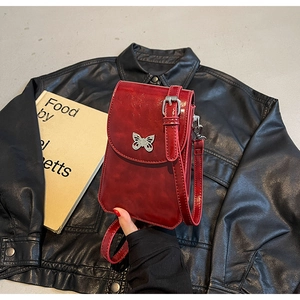 Detailed view of a red patent leather mini crossbody phone bag with silver butterfly clasp