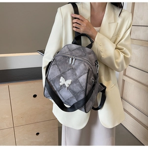 Close-up of grey quilted backpack featuring a white 3D butterfly and adjustable nylon straps