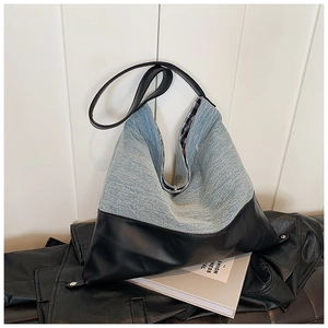 Detail of hobo bag with blue denim and black leather stitching on a minimalist background