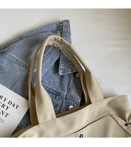 Detail of reinforced wide handles and neat stitching on a khaki faux leather tote bag