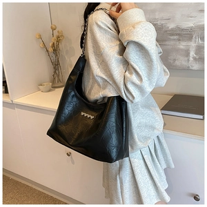 Close-up of black pleated leather tote with silver heart studs and chain strap