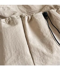 Macro detail of beige nylon pleated fabric with adjustable black drawstring and toggle