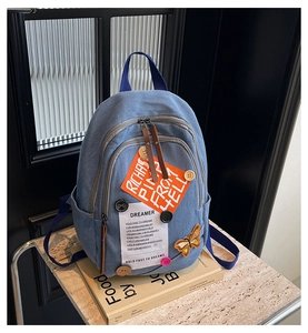 Detail of denim backpack with creative dreamer patches and multi-pocket storage design
