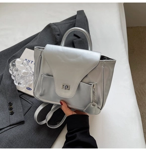 Détail du sac à dos argenté métallisé avec breloque cœur et fermoir rotatif argenté