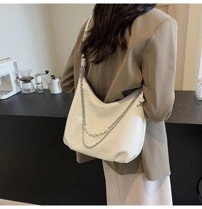 Borsa hobo bianca in ecopelle con catena di perle indossata da una modella donna