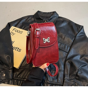 Close-up of a burgundy mini crossbody phone bag featuring a silver butterfly clasp