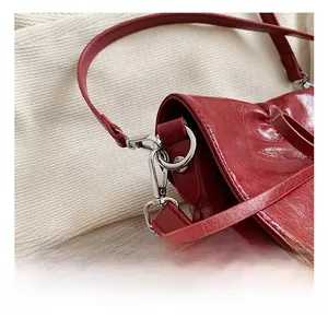 Detailed close-up of the silver metal swivel hook and red glossy PU leather shoulder bag