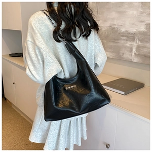 Close-up of black leather hobo bag with heart studs and silver metal chain strap