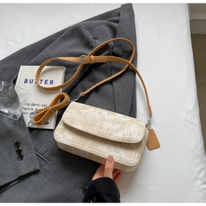 Detailed shot of beige jacquard canvas crossbody bag with brown leather strap and silver buckle