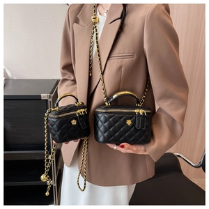 Close-up of black quilted handbags with gold chain straps and camellia flower charms