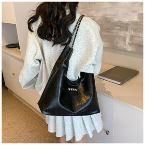 Detailed back view of a black tote bag with silver heart studs and chain strap