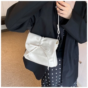 Detail of cream white pleated shoulder bag with bow knot and glossy synthetic leather