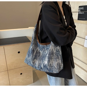 Detail of blue denim hobo bag featuring vertical silver sequins and brown leather strap