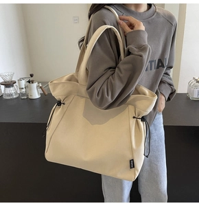 Detail of cream canvas tote bag showing side drawstring and small black Ziyouse brand label