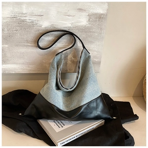 Detail of grey woven fabric and black PU leather stitching on a large tote bag
