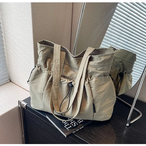 Detail of drawstring canvas tote bag with pleated texture and brand label on side