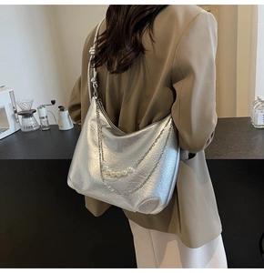 Dettaglio borsa metallizzata argento con catena di perle e tracolla con nodi