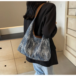 Blue denim tote bag with silver sequin texture and brown leather strap on model