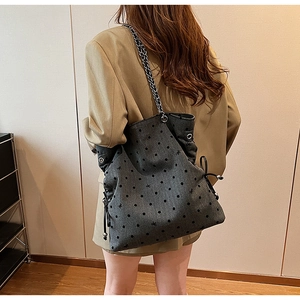 Detail of grey canvas tote featuring black polka dots, bow patterns, and chain strap