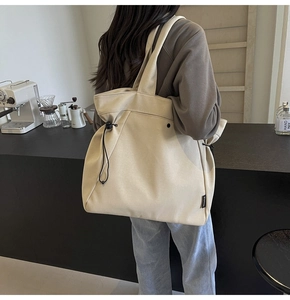 Close-up of beige canvas tote bag with adjustable drawstring and branding detail