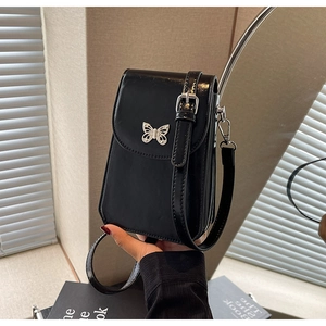 Close-up of black crossbody phone bag featuring a silver butterfly buckle and strap