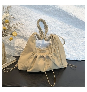 Detail of pleated nylon tote bag featuring elastic ruched handles and drawstring closure