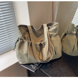 Detail of light khaki tote bag featuring side drawstrings and pleated nylon texture