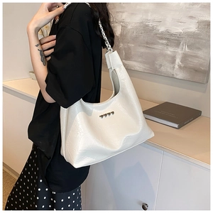 Detail of cream white tote bag with silver heart studs and stylish chain shoulder strap