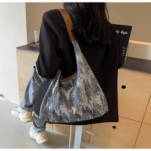 Detail of blue sequined hobo tote bag with brown leather strap worn by a model