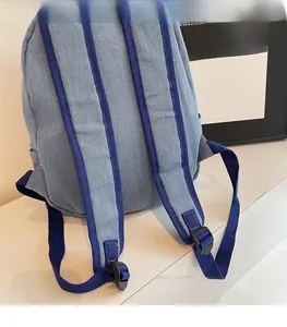 Detail of widened shoulder straps on a denim backpack with adjustable plastic buckles