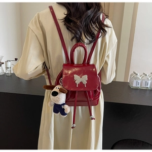 Détail d'un mini sac à dos en cuir verni bordeaux avec boucle papillon argentée