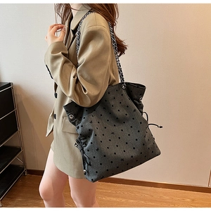 Detail of grey tote bag featuring black polka dots and silver chain shoulder strap