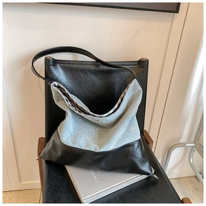 Detail of denim tote bag with black leather bottom and checkered lining on chair