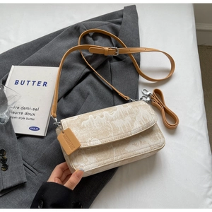 Detail of marble pattern crossbody bag placed on a grey blazer with a decor book