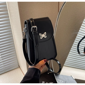 Detail of black glossy leather mini phone bag with silver butterfly clasp and slim strap